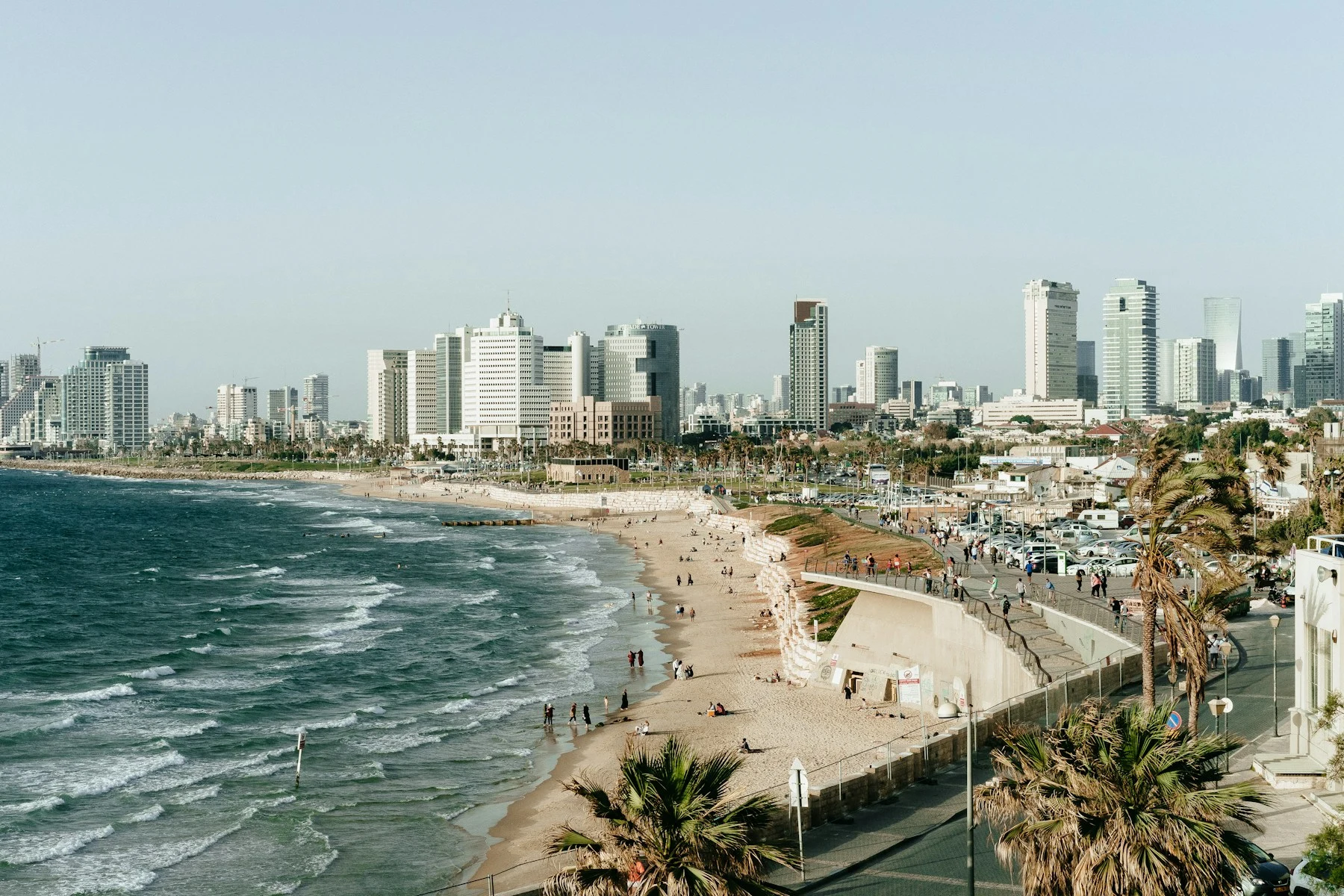 Promeneurs et baigneurs sur le front de mer de Tel-Aviv-Jaffa, entre palmiers et immeubles