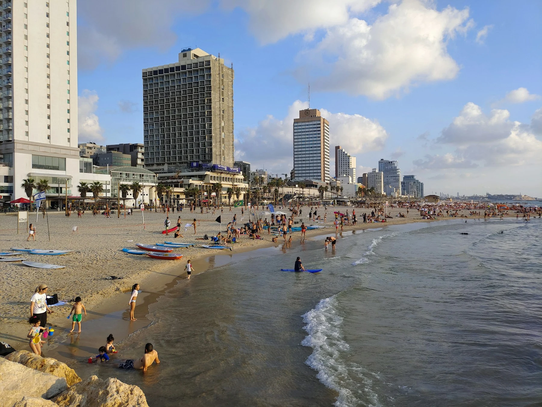 Baignade, jeux et promenades sur une plage de Tel-Aviv, avec la ville en arrière-plan
